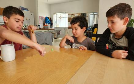 Group of children collaborating on a brain game at a table, demonstrating teamwork and engagement.